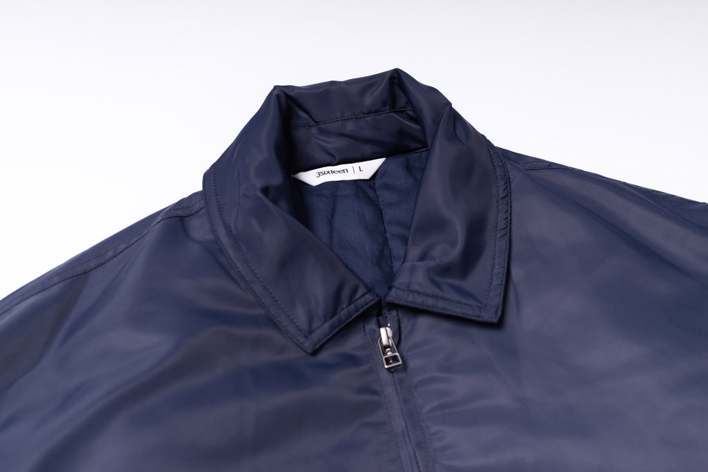 Navy blue jacket with a zipper on a light gray background