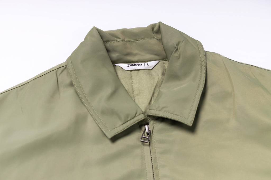 Close-up of a green jacket collar with a brand label on a white background