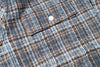 Close-up of a textured fabric with a button, featuring blue and brown plaid pattern.