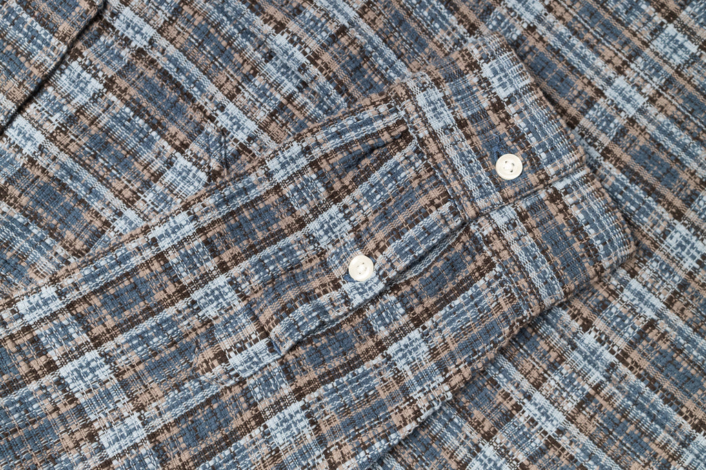 Close-up of a plaid fabric with a checkered pattern in blue and brown tones.