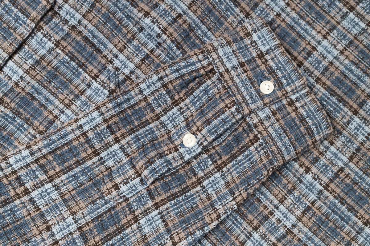 Close-up of a plaid fabric with a checkered pattern in blue and brown tones.