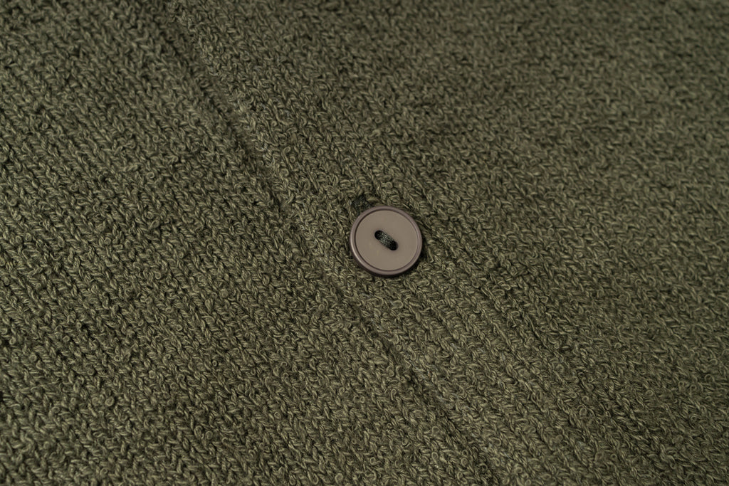 Close-up of a button on a textured green fabric
