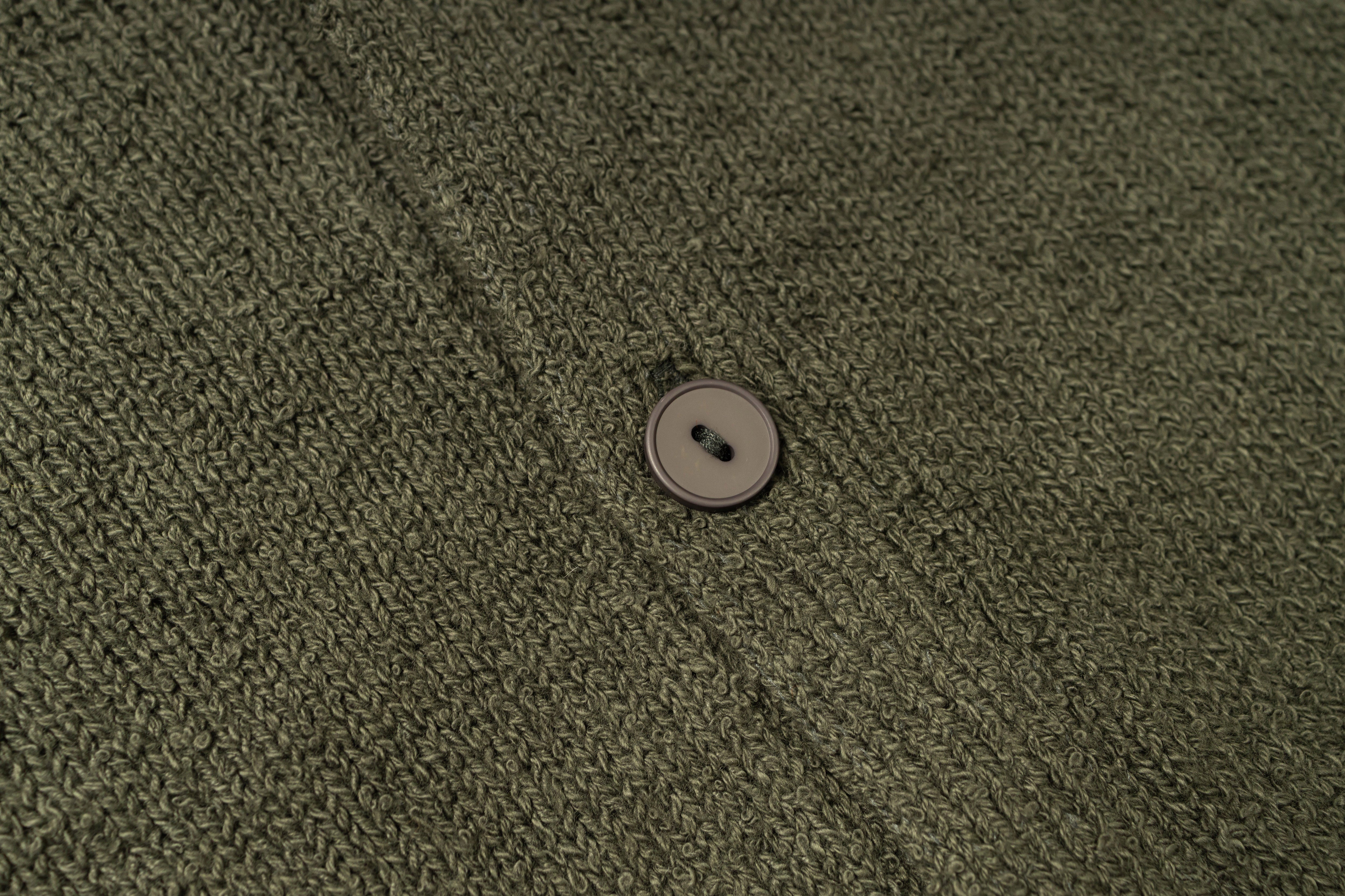 Close-up of a button on a textured green fabric