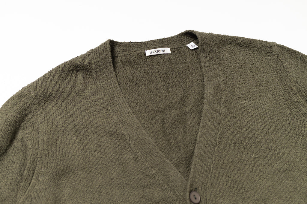 Green cardigan with a brand label on a white background
