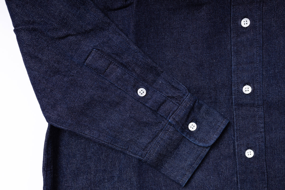 Close-up of a navy blue shirt with rolled-up sleeve cuffs on a white background