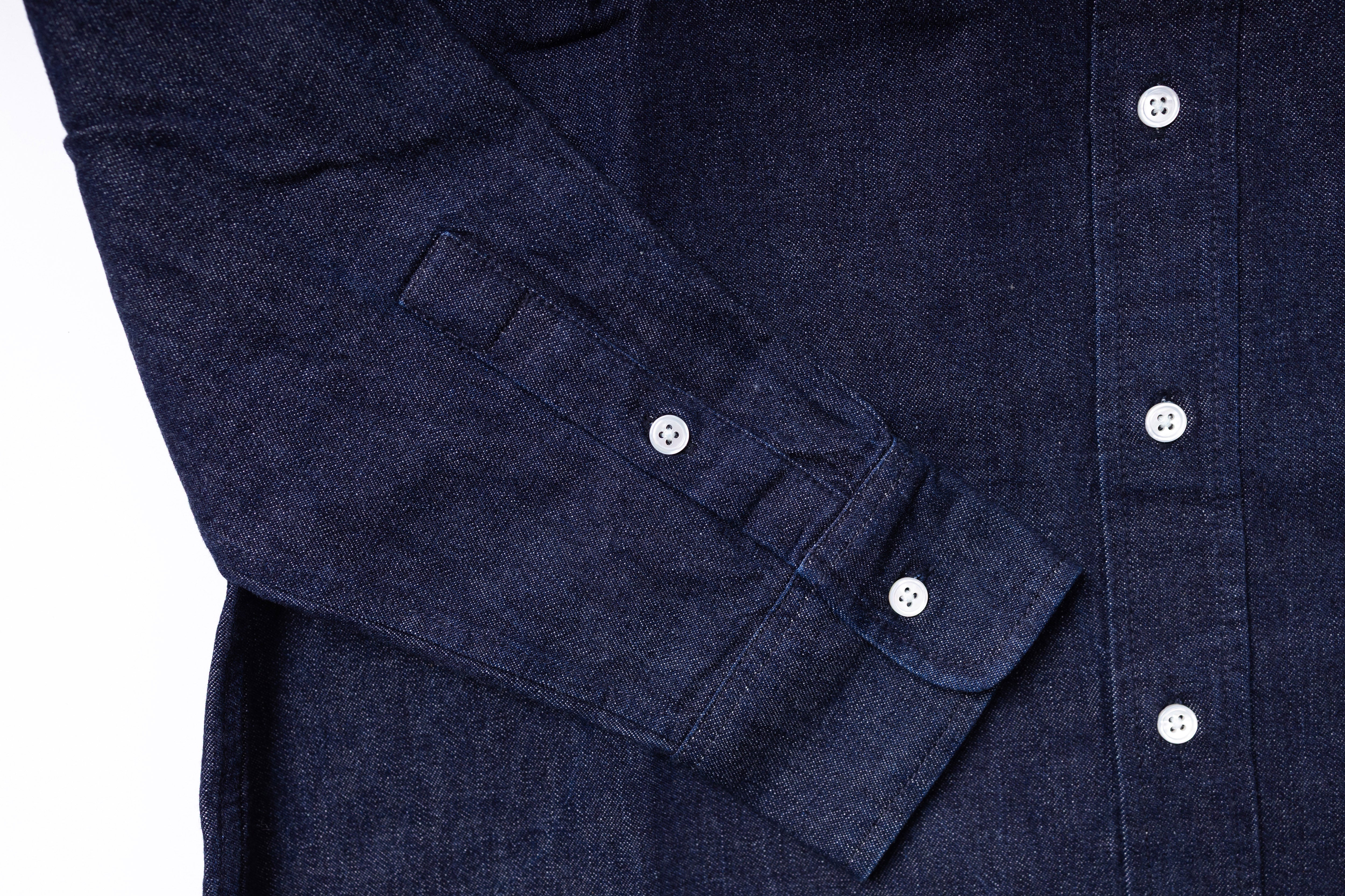Close-up of a navy blue shirt with rolled-up sleeve cuffs on a white background