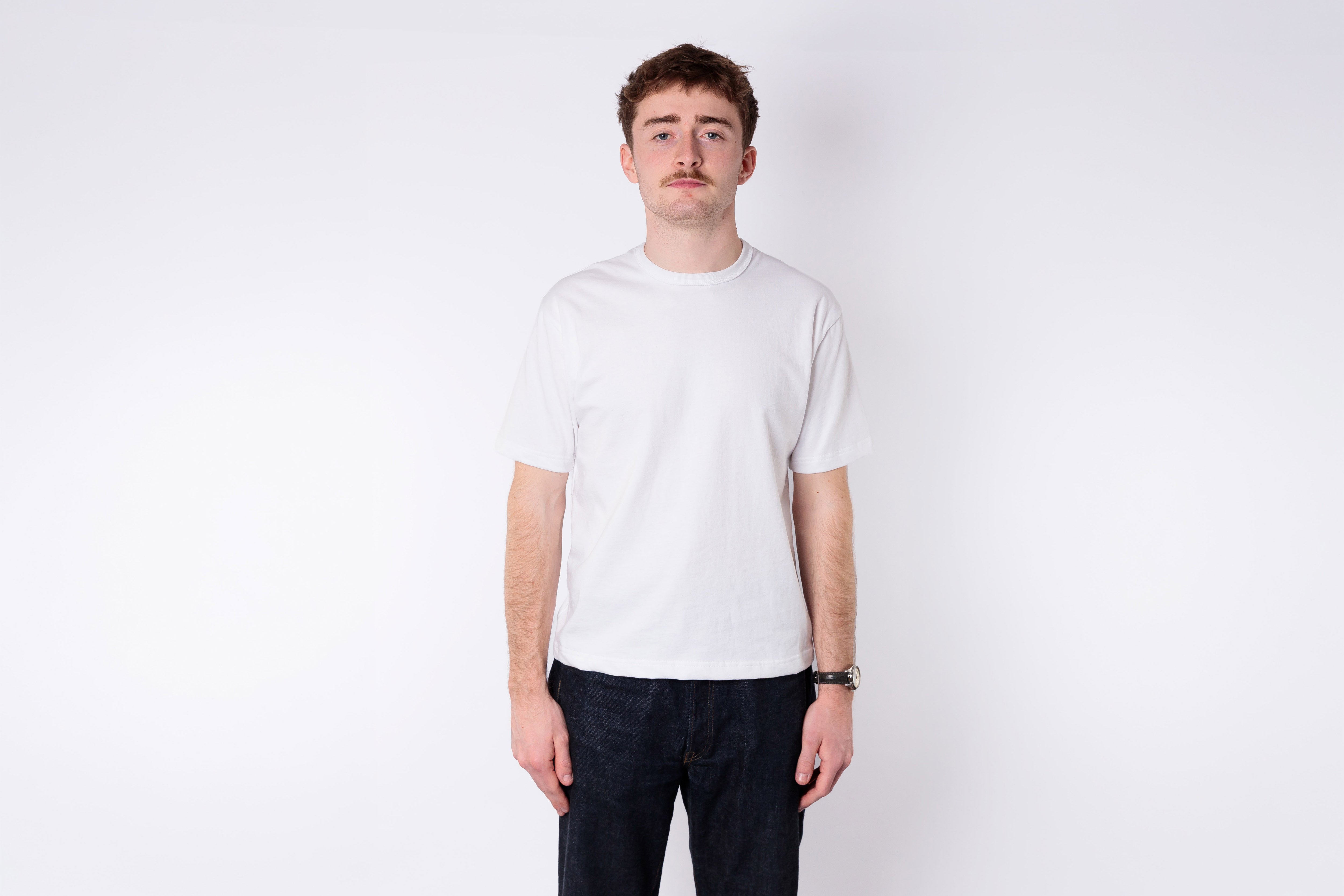 A man wearing a boxy white tshirt on a white background