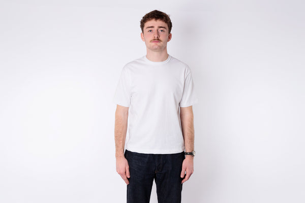 A man wearing a boxy white tshirt on a white background