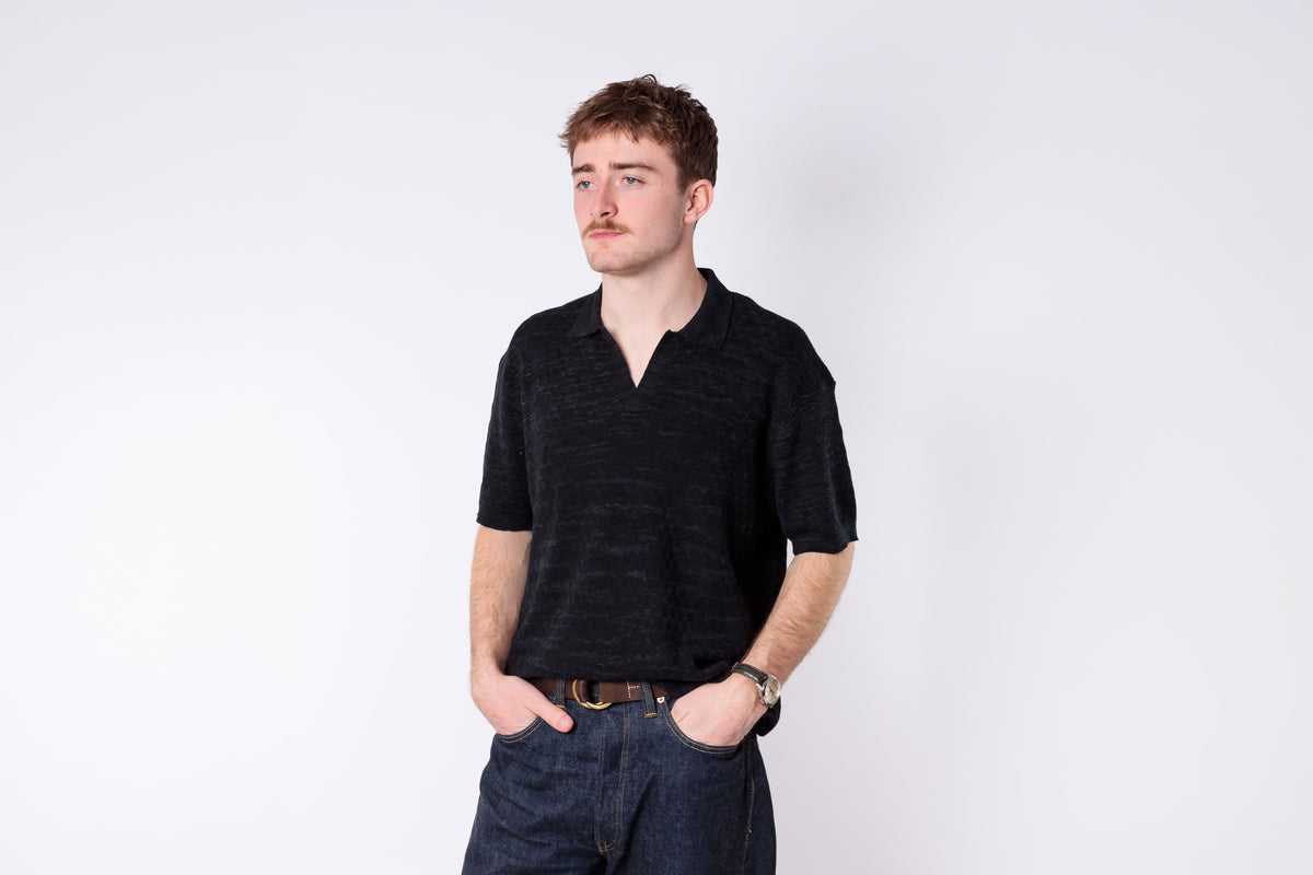 Man wearing a black shirt and dark pants on a white background