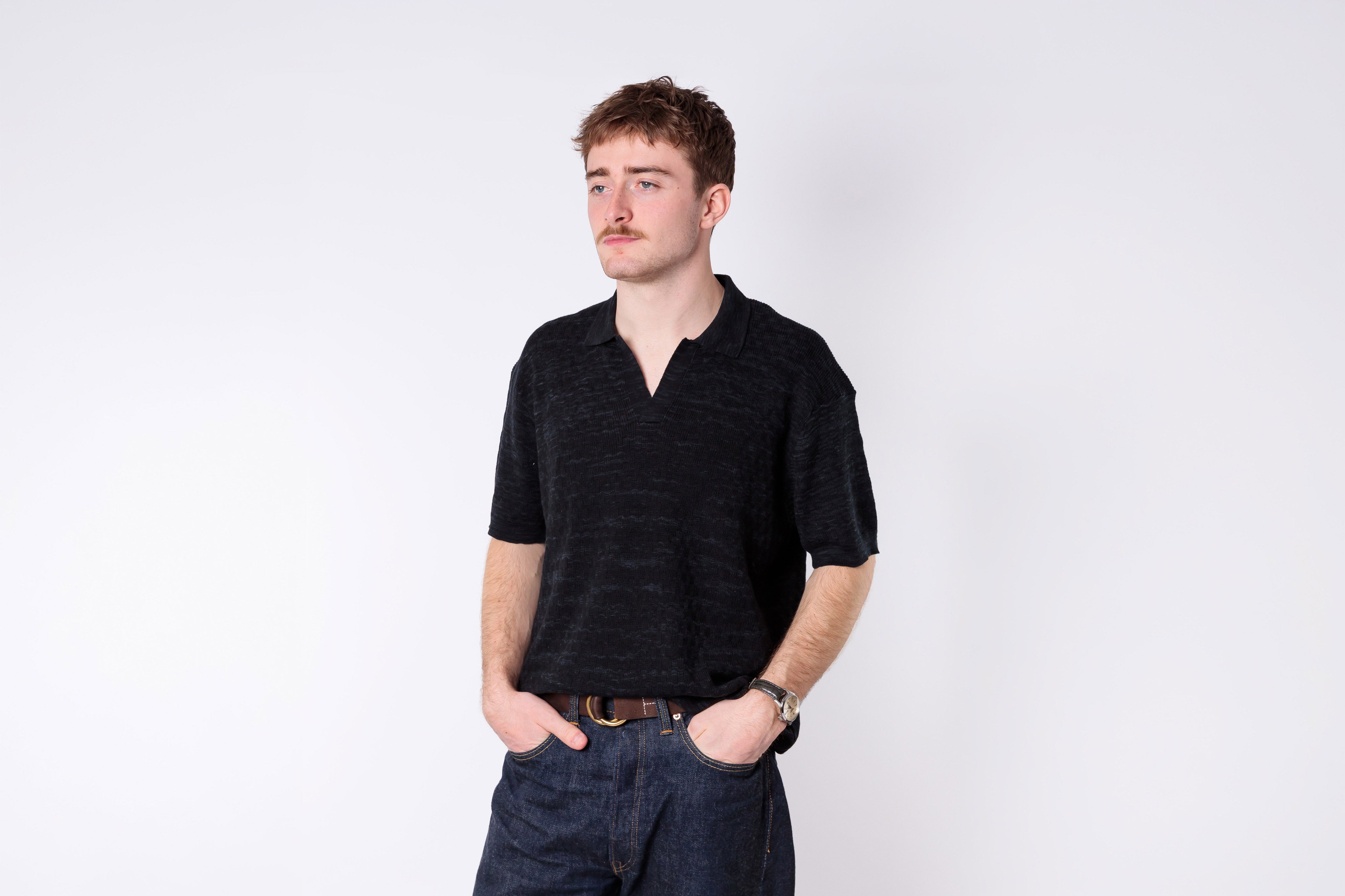 Man wearing a black shirt and dark pants on a white background