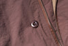 Close-up of a button and zipper on a brown fabric surface
