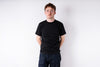 Person wearing a black t-shirt and dark jeans against a white background
