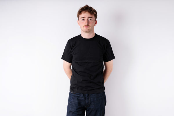 Person wearing a black t-shirt and dark jeans against a white background