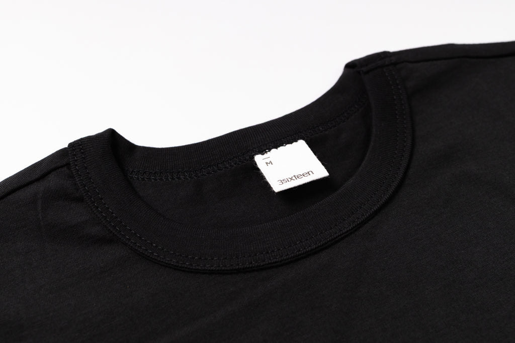 Black t-shirt with a brand label on a white background