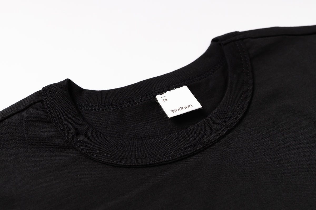 Black t-shirt with a brand label on a white background