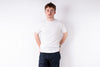 Person wearing a white t-shirt and dark pants on a plain background