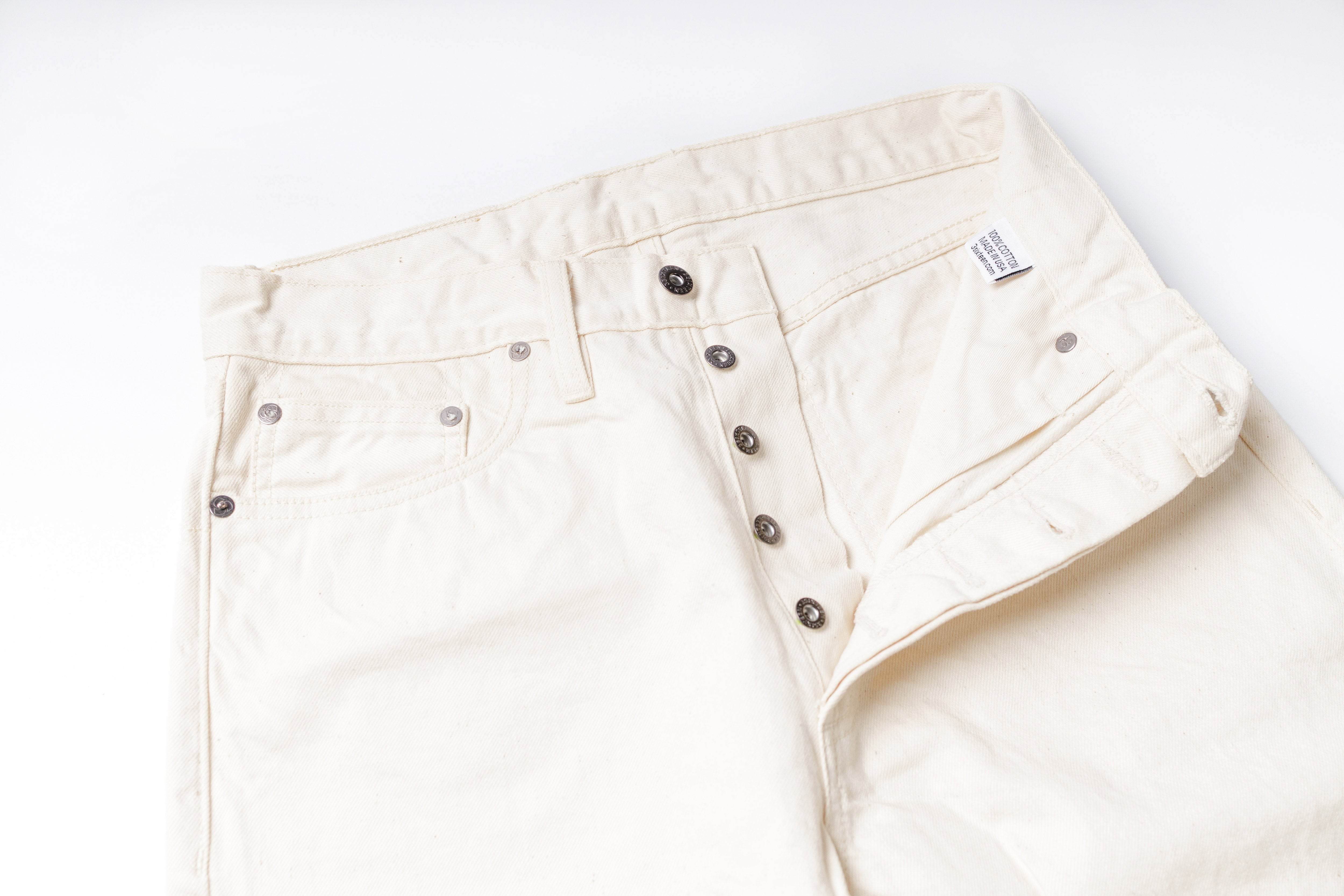 Close-up of a pair of beige pants with buttons on a white background