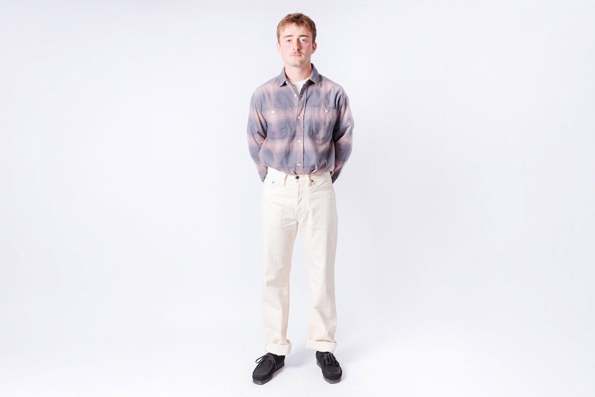 Man wearing a plaid shirt and white pants on a white background