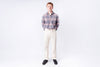 Man wearing a plaid shirt and white pants on a white background