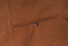 Close-up of a brown textured fabric with a button on a pocket.