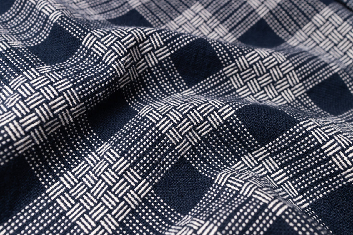 Close-up of a woven fabric with a navy blue and white plaid pattern, showing the texture and weave details.