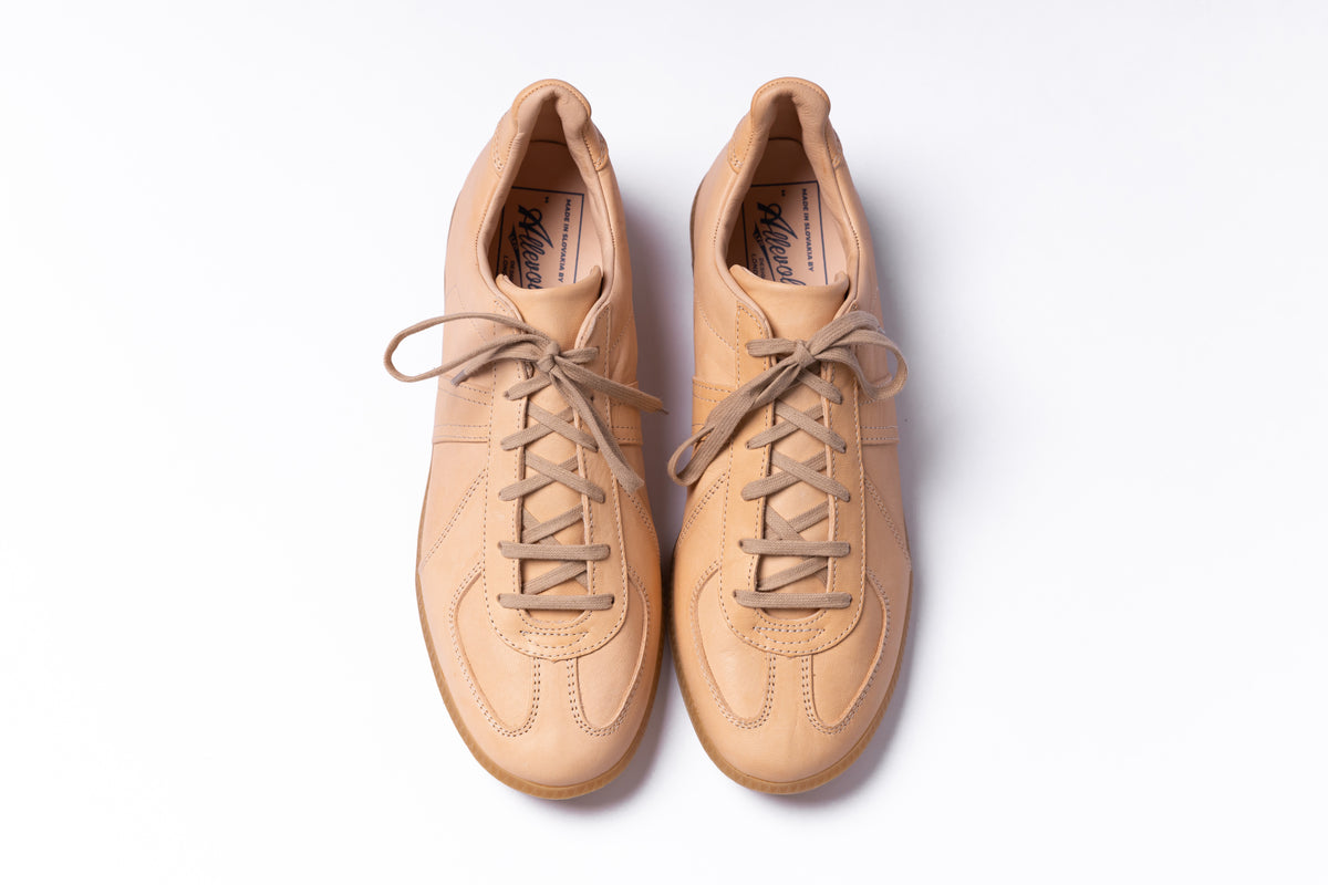 A pair of tan leather low-top sneakers with matching laces, photographed from a top-down perspective on a clean white background.