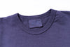 Close-up of a blue t-shirt collar with a brand label on a white background
