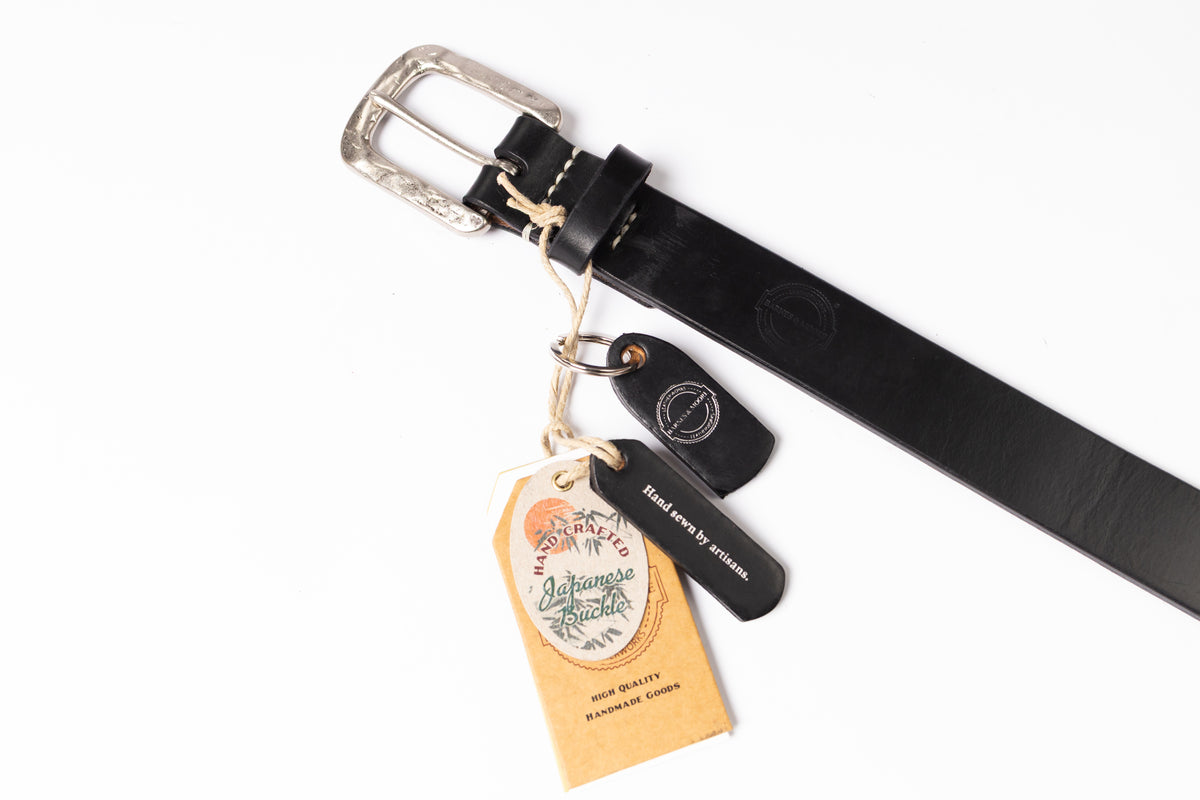 A black leather belt with a silver-toned buckle, shown on a white background with attached paper tags and a small black leather tag.