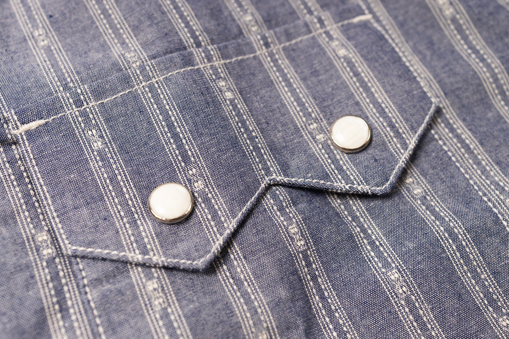 Close-up of a blue checkered shirt with buttons on a textured fabric background