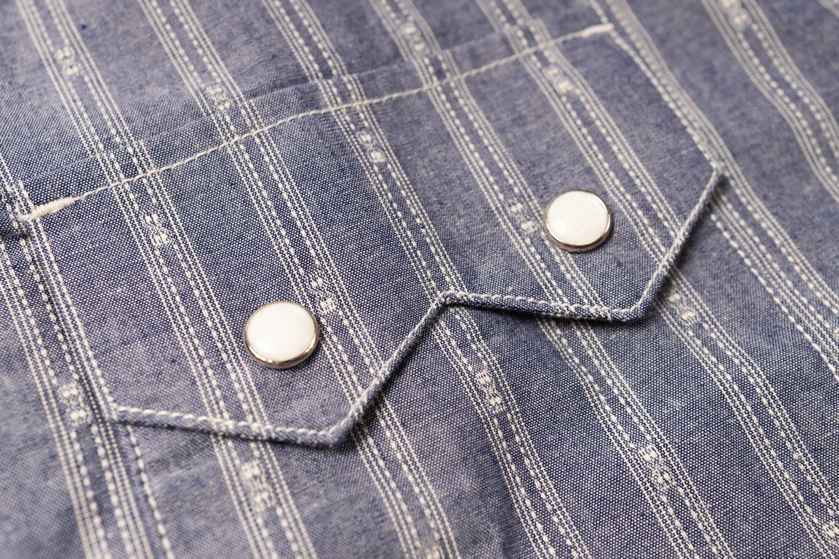 Close-up of a blue checkered shirt with buttons on a textured fabric background