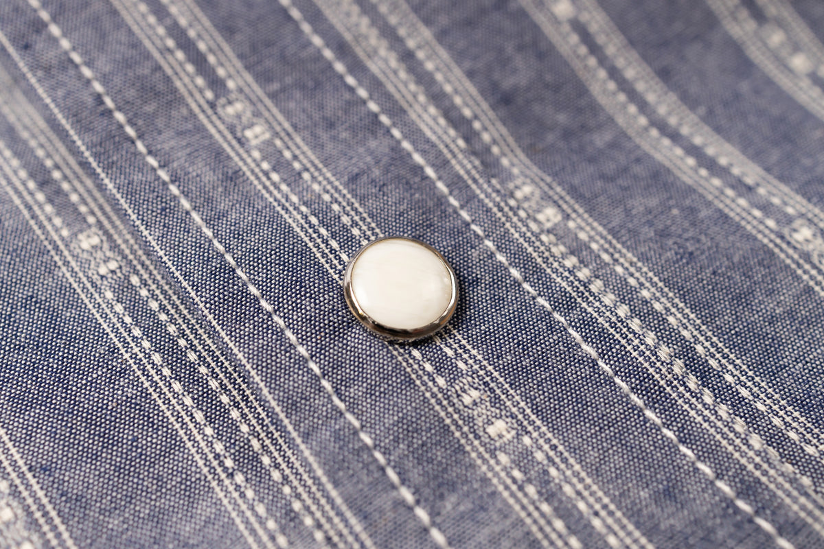 Close-up of a button on blue denim fabric