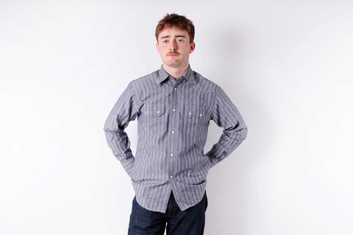 Man wearing a striped shirt and dark pants against a white background