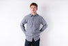 Man wearing a striped shirt and dark pants against a white background