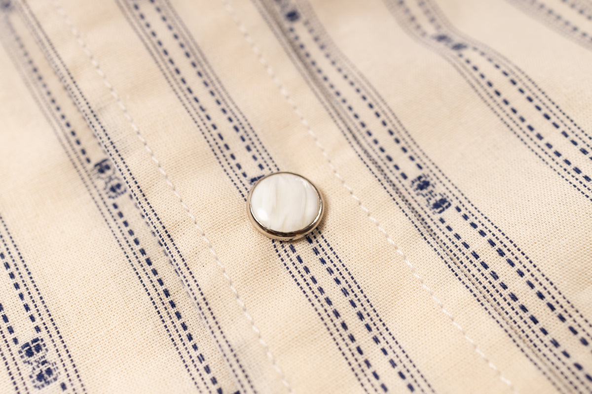 Close-up of a button on a striped fabric shirt
