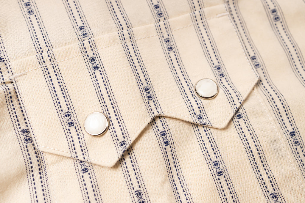 Close-up of a beige fabric with blue stripes and white buttons