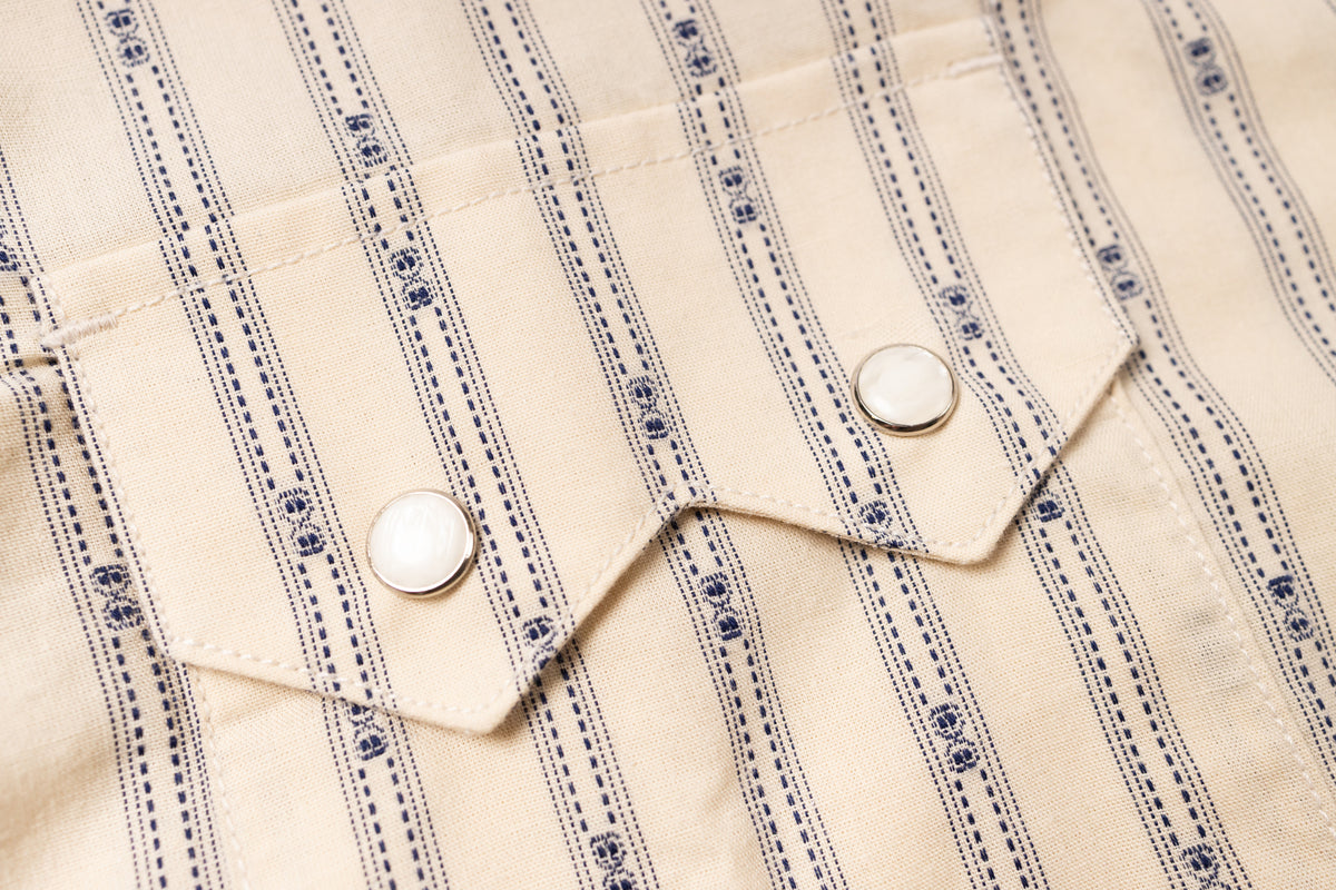 Close-up of a beige fabric with blue stripes and white buttons