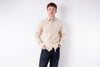 Man wearing a beige button-up shirt and dark pants on a white background