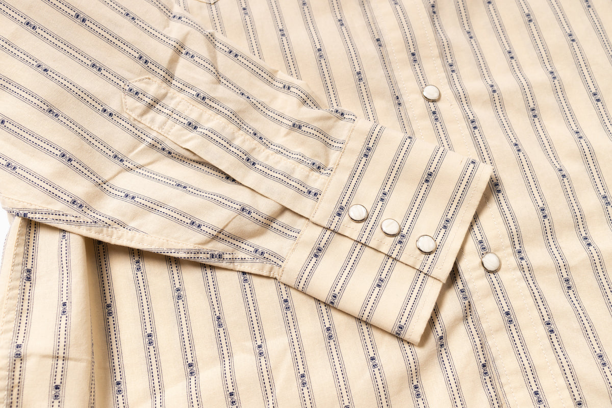 Close-up of a beige shirt with blue stripes and buttons.
