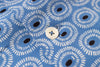 Close-up of blue fabric with white circular pattern and black dots, featuring a button.