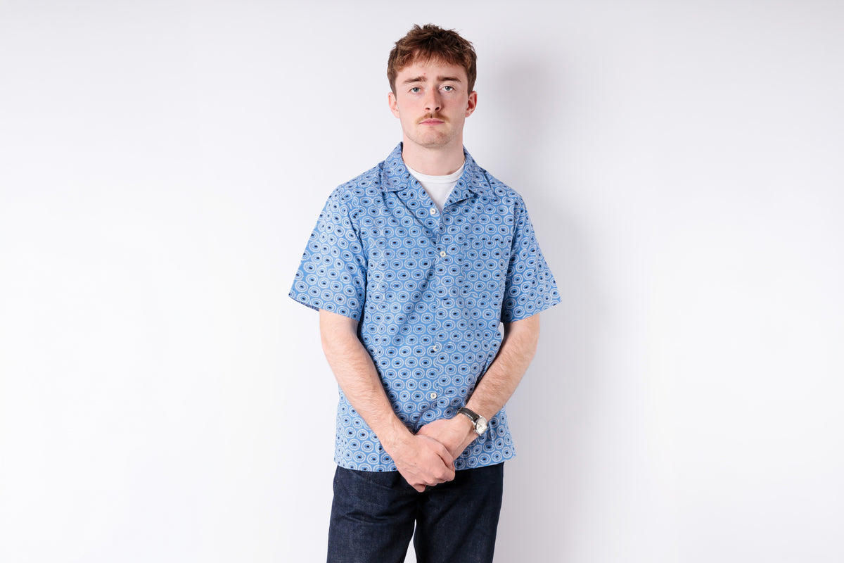 Person wearing a blue patterned shirt against a white background