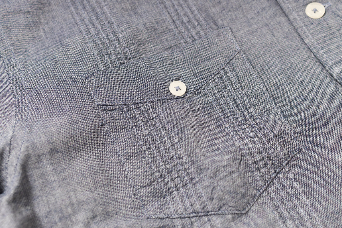 Close-up of a gray shirt with a pocket and button