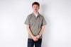Man wearing a patterned shirt and dark pants on a white background
