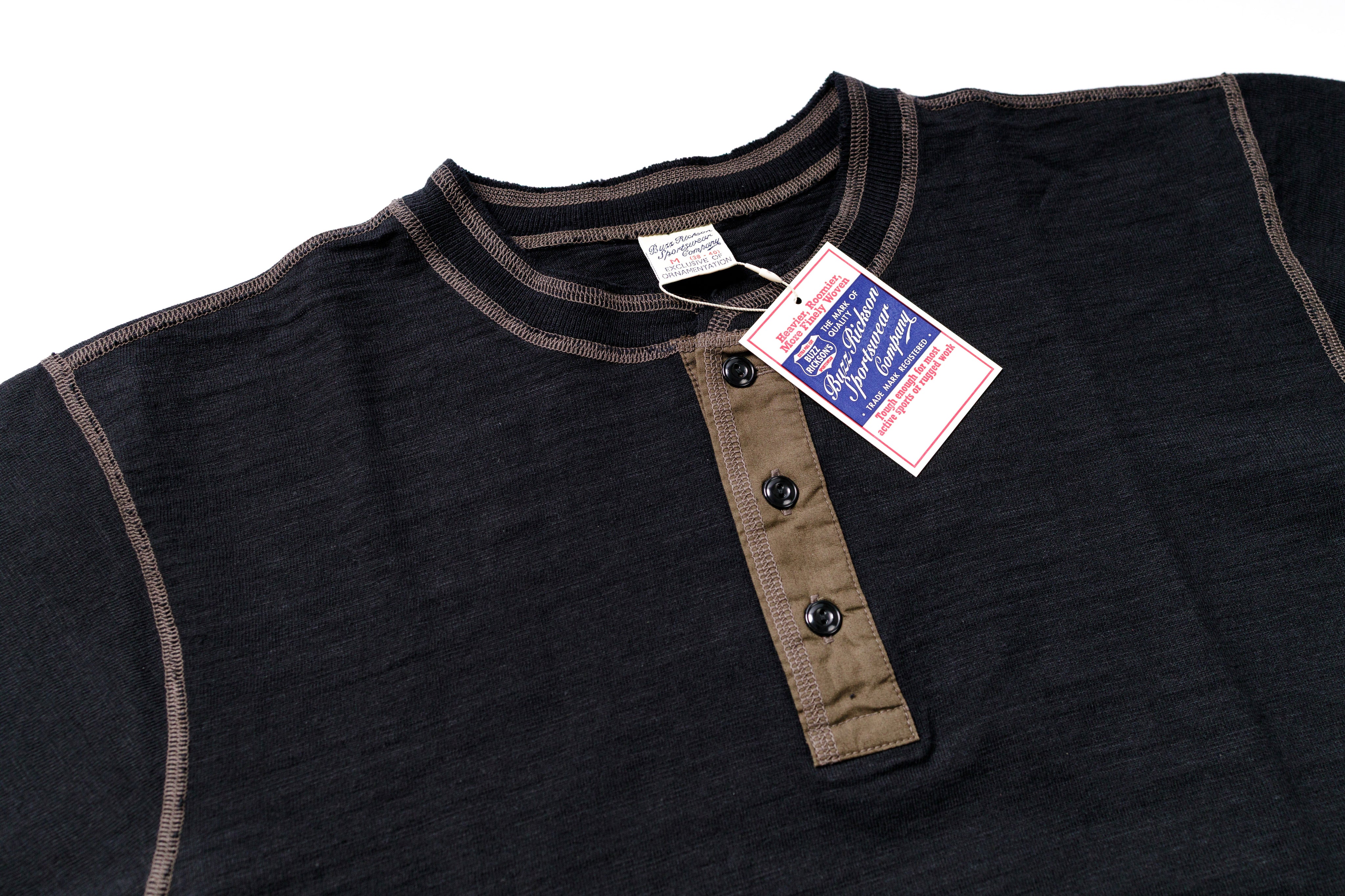 Black shirt with brown trim and buttons, tag attached on a white background