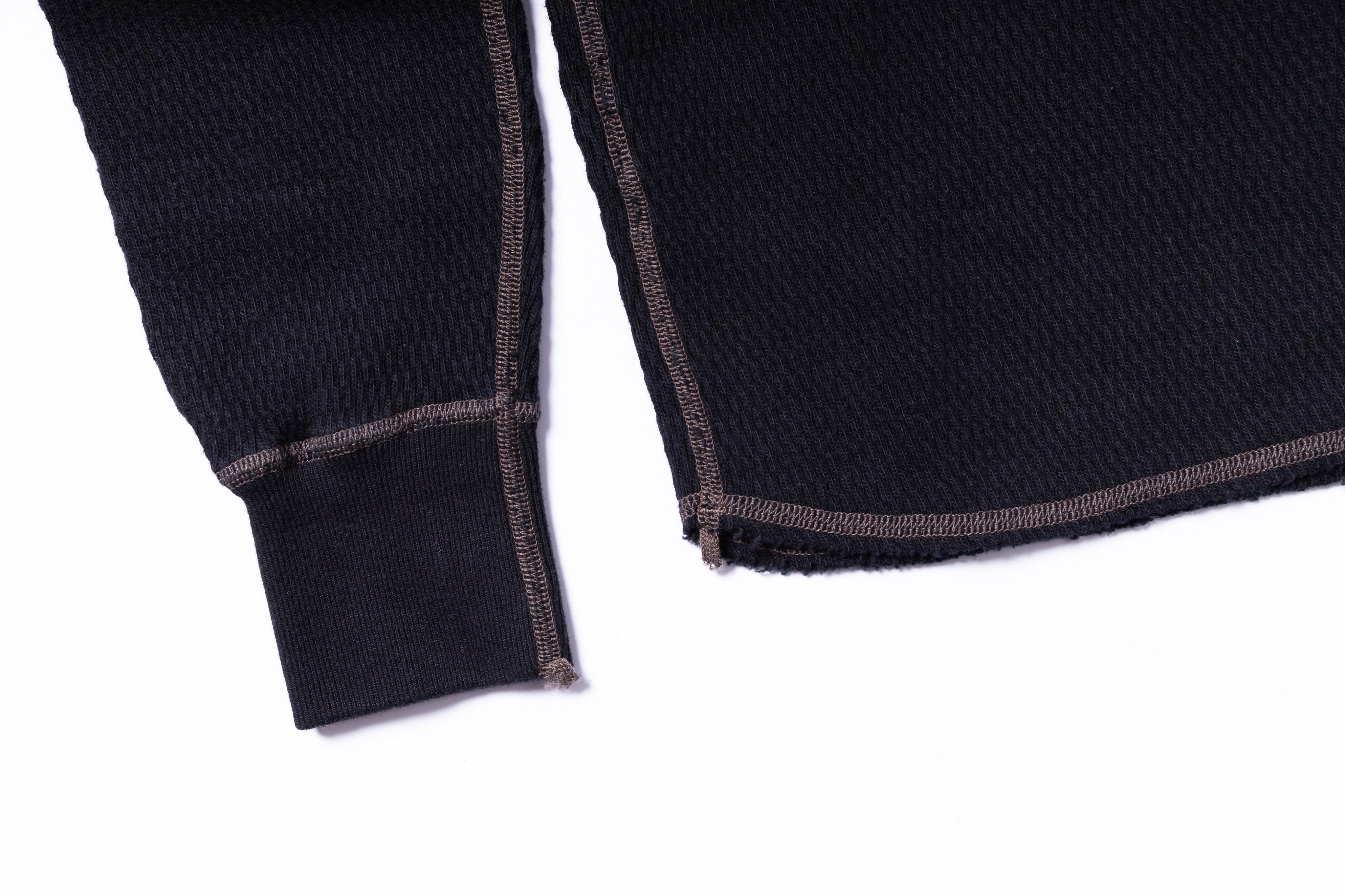 Close-up of a black sweater with brown trim on a white background