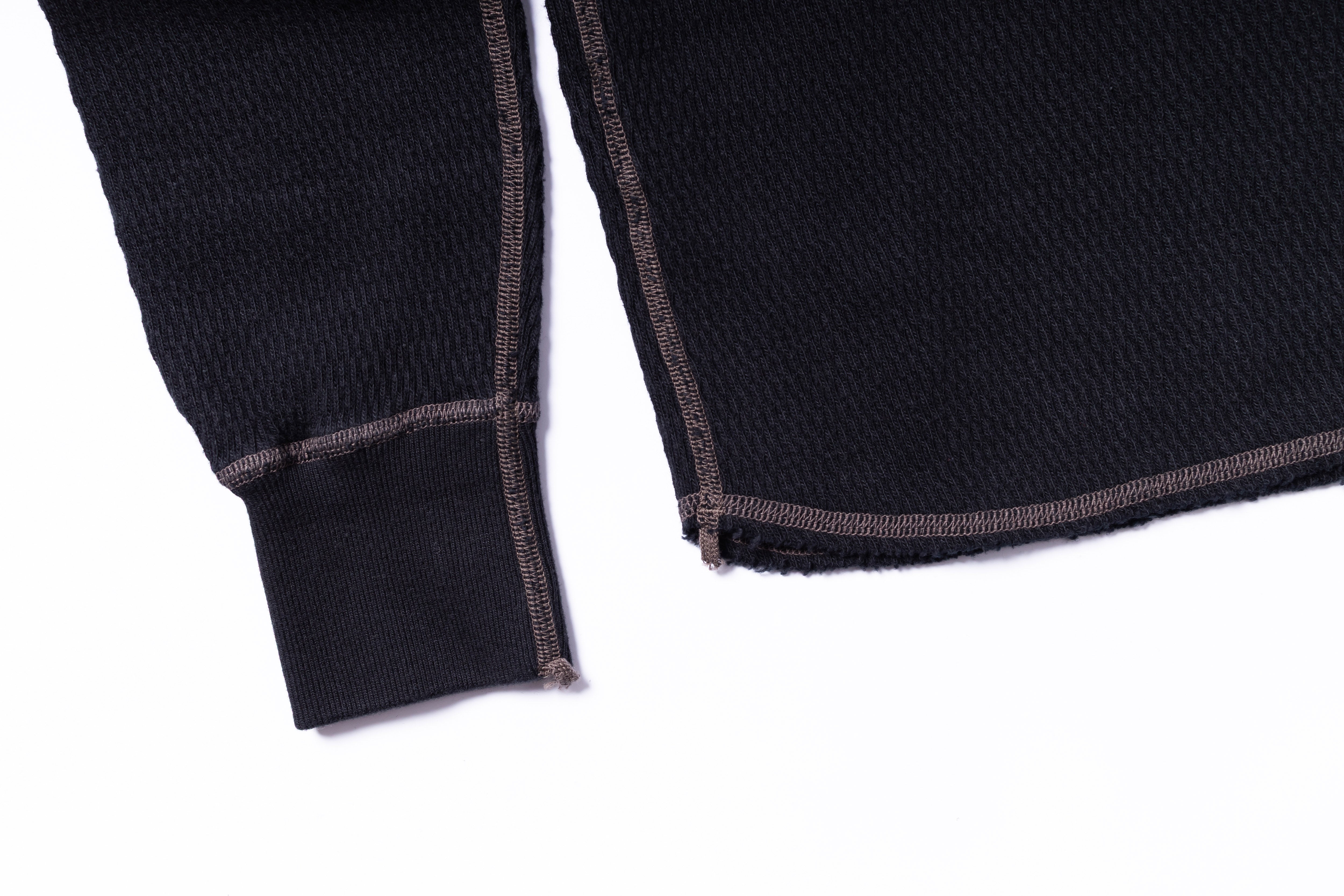 Close-up of a black sweater with brown trim on a white background