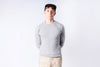 Person wearing a gray sweater and beige pants against a white background