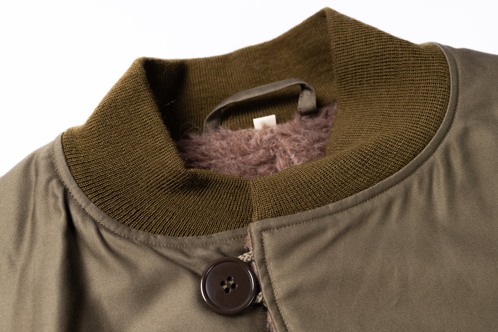 Close-up of a brown jacket with a button and plaid lining on a white background