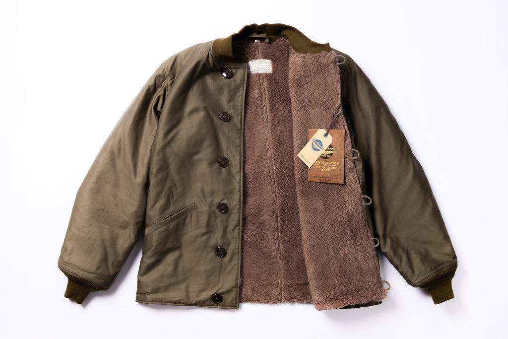 Green jacket with brown lining and a visible brand tag on a white background