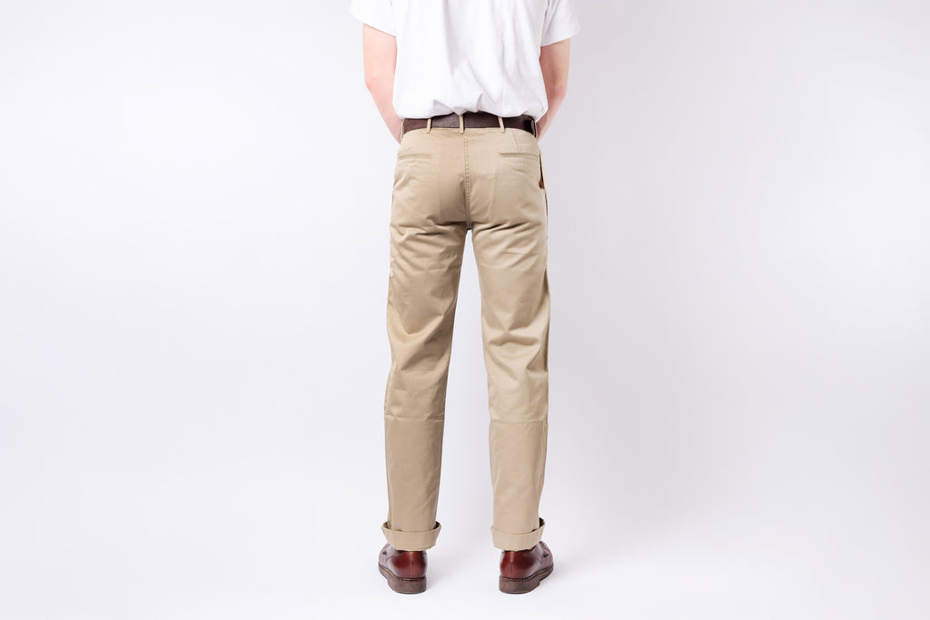 Person wearing beige pants and a white shirt on a plain background