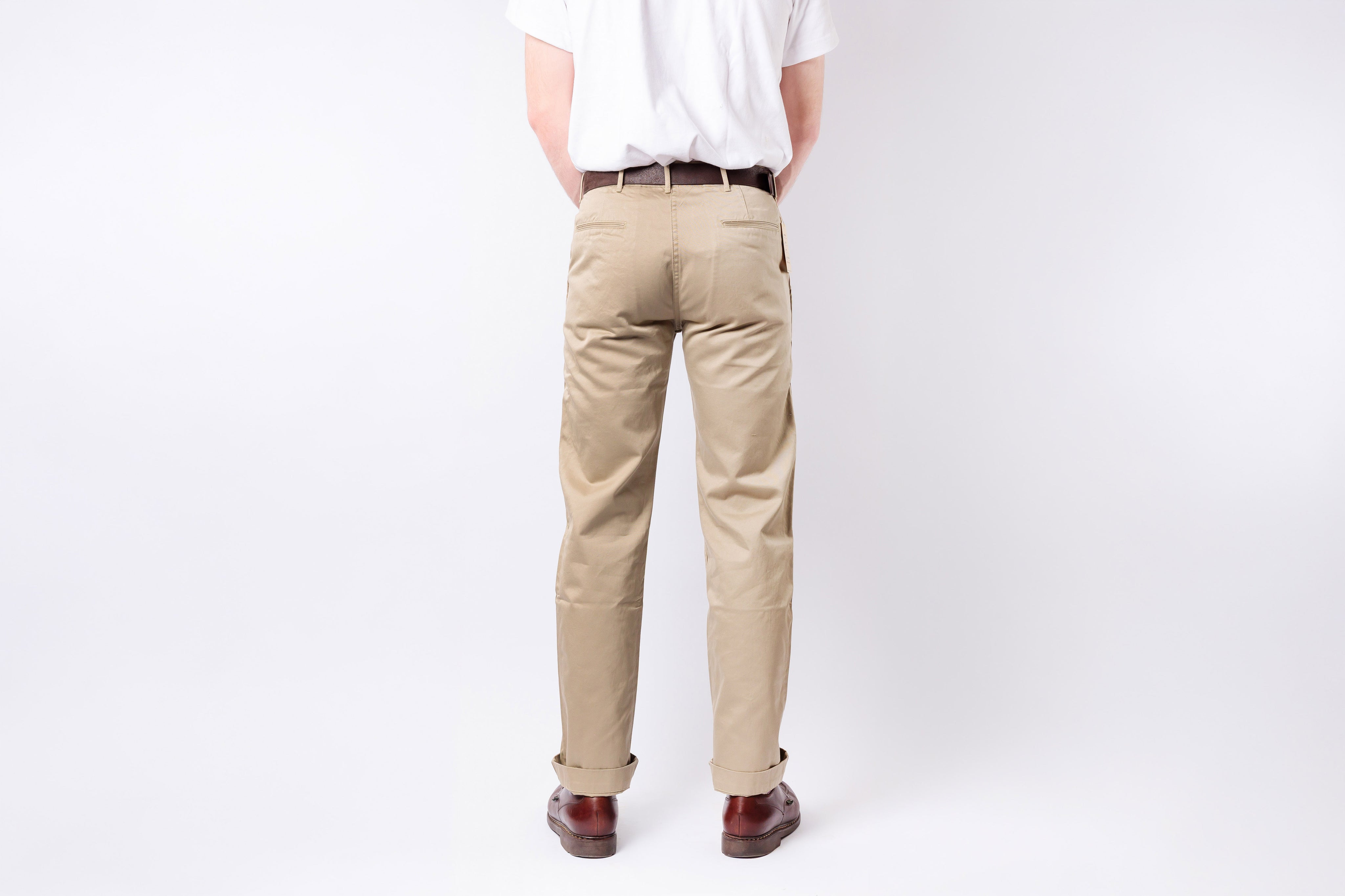 Person wearing beige pants and a white shirt on a plain background